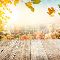 Wooden table with autumn leaves background