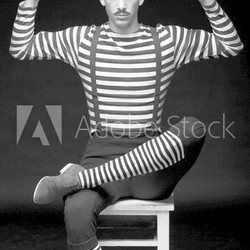 Morose circus performer sitting in a striped dress