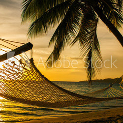 Hammock silhouette with palm trees on a beach at sunset