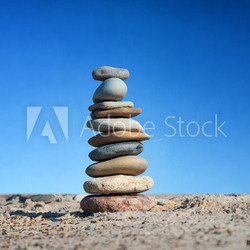 Steinpyramide im Sand vor schönem blauen Himmel