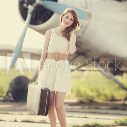 Lonely girl with suitcase at near airplane.