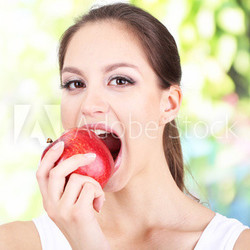 Young woman with apple on bright background
