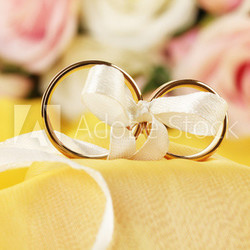 Wedding rings tied with ribbon on bright background