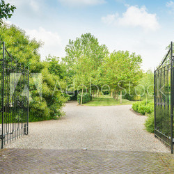 Opened black wrought iron gate of a large estate