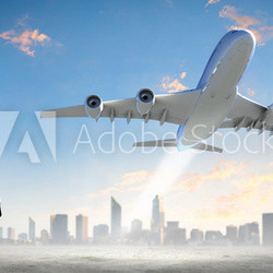 Business woman looking at airplane in sky