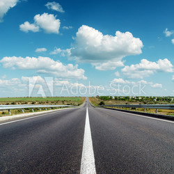 black asphalt road to horizon under deep blue cloudy sky