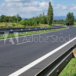 Empty highway passing landscape trees