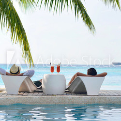 happy young couple relax and take fresh drink on poolside